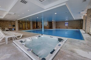 A swimming pool with a hot tub, lounge chairs, and a stone wall. - Hotel Shipka All Inclusive (Varna)