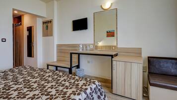 A hotel room with a bed, a desk, a television, a mirror, and a seating area.