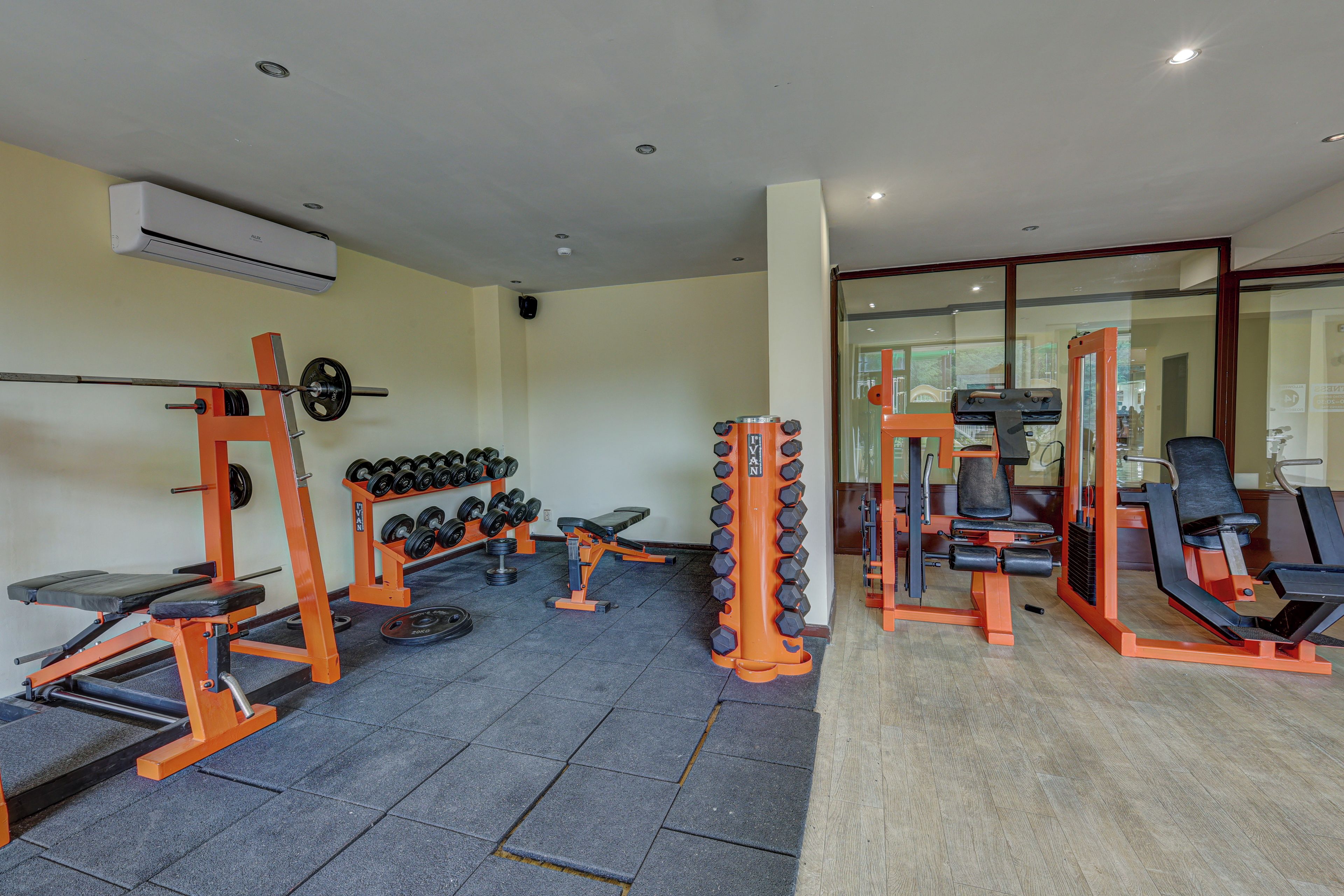 Un gimnasio con equipo de levantamiento de pesas, bancos y mancuernas.