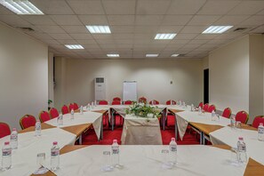 Un salón de conferencias con mesas dispuestas para reuniones, equipado con botellas de agua y tarjetas de identificación.