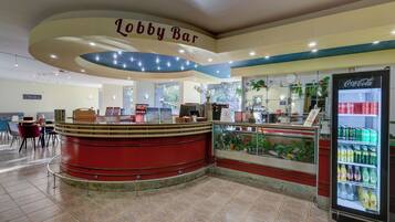 Eine Lobbybar mit einem Coca-Cola-Kühlschrank, Sitzgelegenheiten und einer Theke mit verschiedenen Artikeln.