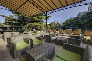 Un espacio de estar al aire libre con mobiliario de mimbre y un toldo.