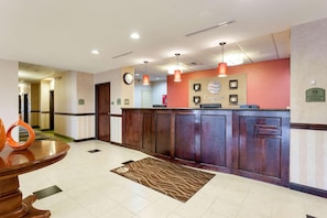 Zona de recepción con un mostrador de madera, un reloj y el letrero de recepción.