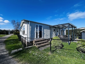 A single-story mobile home with a covered porch and a fenced yard. - RBR 264 - Beach Resort Kamperland by Interhome (Kamperland)