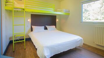 A bunk bed with a ladder, a single bed, white bedding, a window with a view, and a radiator.
