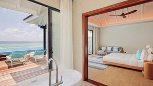 A modern hotel room with a balcony, a large bathtub, and a bed with a view of the ocean. - Nova Maldives (Malé)