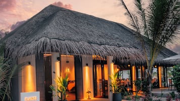 A thatched-roof building with a sign reading 'Flames Grill House.'