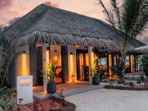 A thatched-roof building with a sign reading 'Flames Grill House.' - Nova Maldives (Malé)