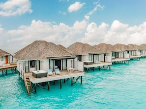 Overwater bungalows with wooden decks and lounge chairs, connected by walkways. - Nova Maldives (Malé)