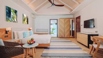A modern hotel room with a bed, a dining area, a TV, and a view of the outdoors.