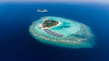 An aerial view of a tropical island with a crescent-shaped resort area featuring overwater bungalows and a central building.