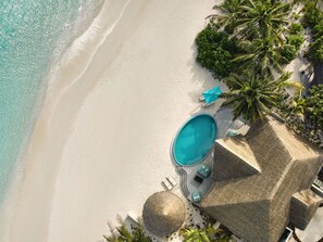 An aerial view of a beachside resort with a swimming pool, lounge chairs, and palm trees. - Nova Maldives (Malé)
