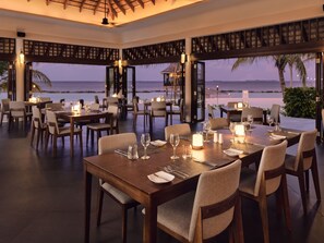 A restaurant with tables set for dining, overlooking a beach. - Nova Maldives (Malé)