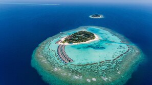 An aerial view of a tropical island resort with a crescent-shaped beach, overwater bungalows, and a small island in the background. - Nova Maldives (Malé)