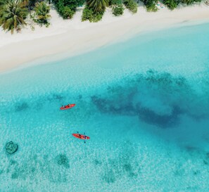 An aerial view of a beach with clear turquoise water, white sand, and two red kayaks. - Nova Maldives (Malé)