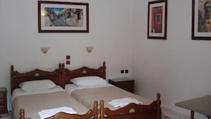 Ein Zimmer mit zwei Holzbett, einem kleinen Tisch und Wandlampen.