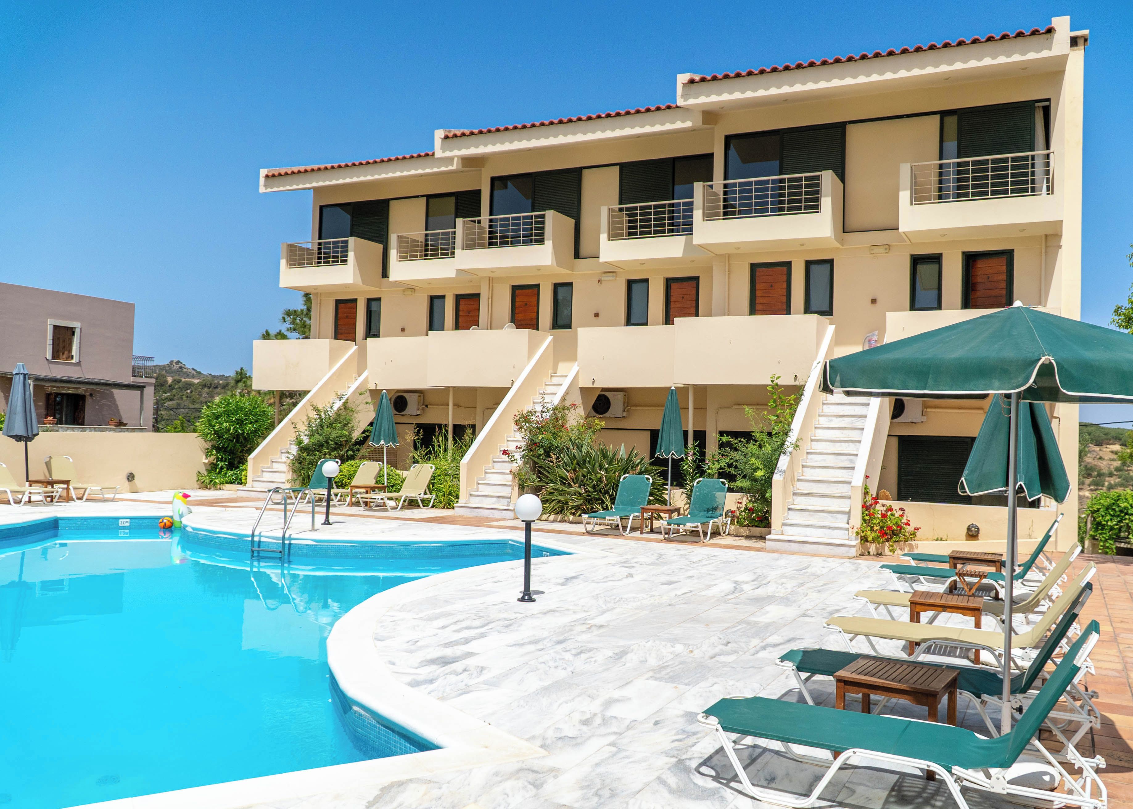 A hotel with a swimming pool, sun loungers, and a staircase leading to the upper floors.