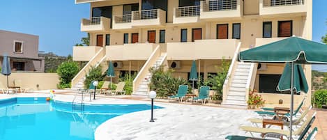 Un hotel con piscina, tumbonas y una escalera que conduce a los pisos superiores.
