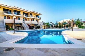 A swimming pool area with a building in the background. - Orestis (Chania)