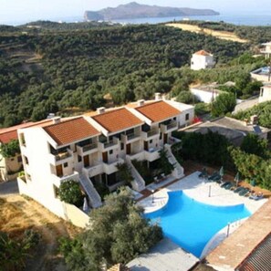 A multi-story building with a swimming pool, surrounded by greenery and a view of the sea. - Orestis (Chania)