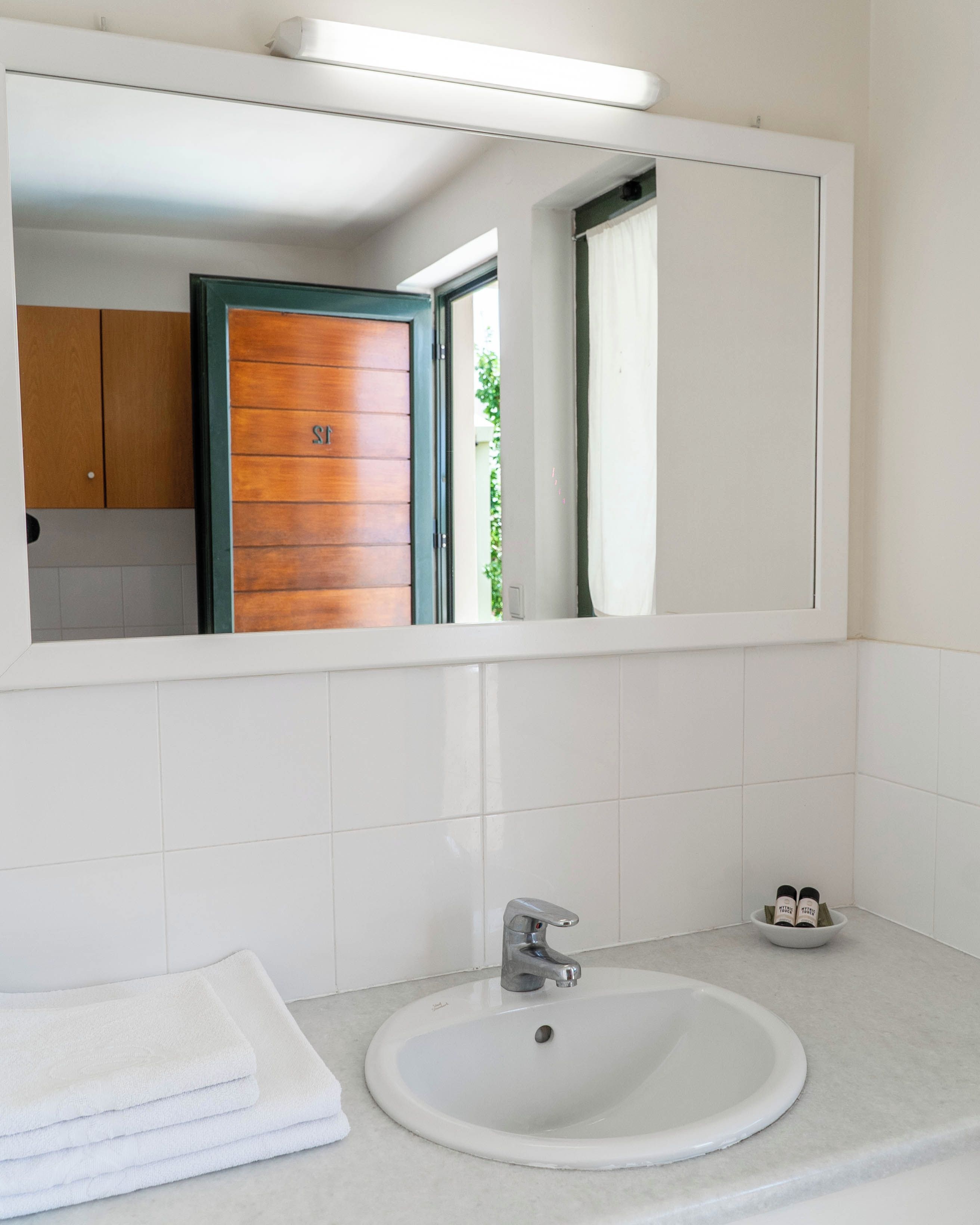 Een badkamer met een wit wastafel, een spiegel en een stap handdoeken.