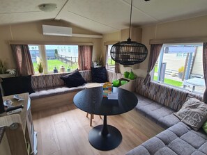 Een gezellige woonkamer met een bank, een ronde tafel en een hanglamp.