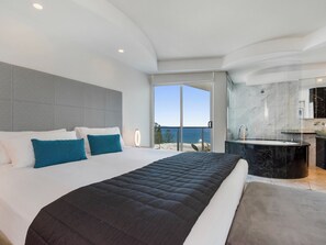 A modern hotel room with a large bed, a bathroom with a bathtub, and a view of the sea. - Mantra Sirocco Mooloolaba (Sunshine Coast)