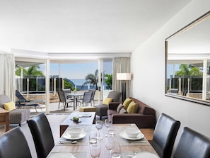 A hotel room with a dining area, a sofa, and a large window with a view of the sea. - Mantra Zanzibar Mooloolaba (Sunshine Coast)