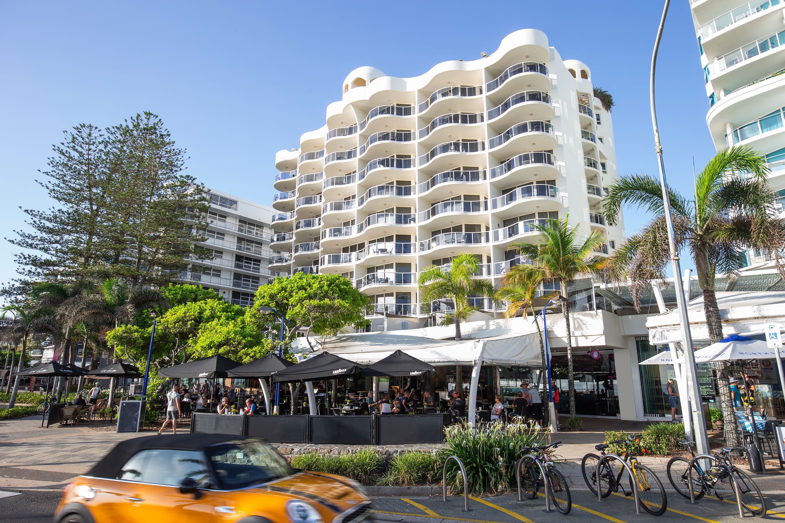 A modern building with multiple balconies and a covered outdoor seating area.