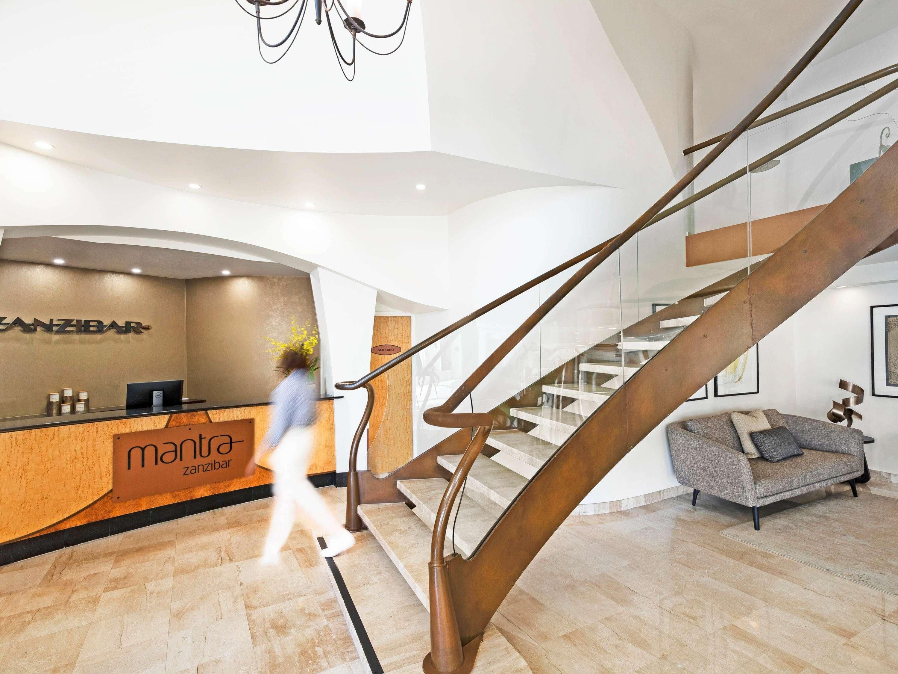 Ein modernes Interieur mit einer Rezeption, einer Treppe und einer Sitzecke.