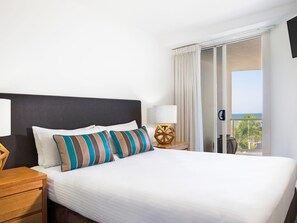 A hotel room with a bed, a nightstand, a lamp, and a view of the sea. - Mantra Zanzibar Mooloolaba (Sunshine Coast)