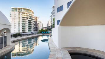 Un edificio moderno con piscina, varios balcones y cielo despejado.