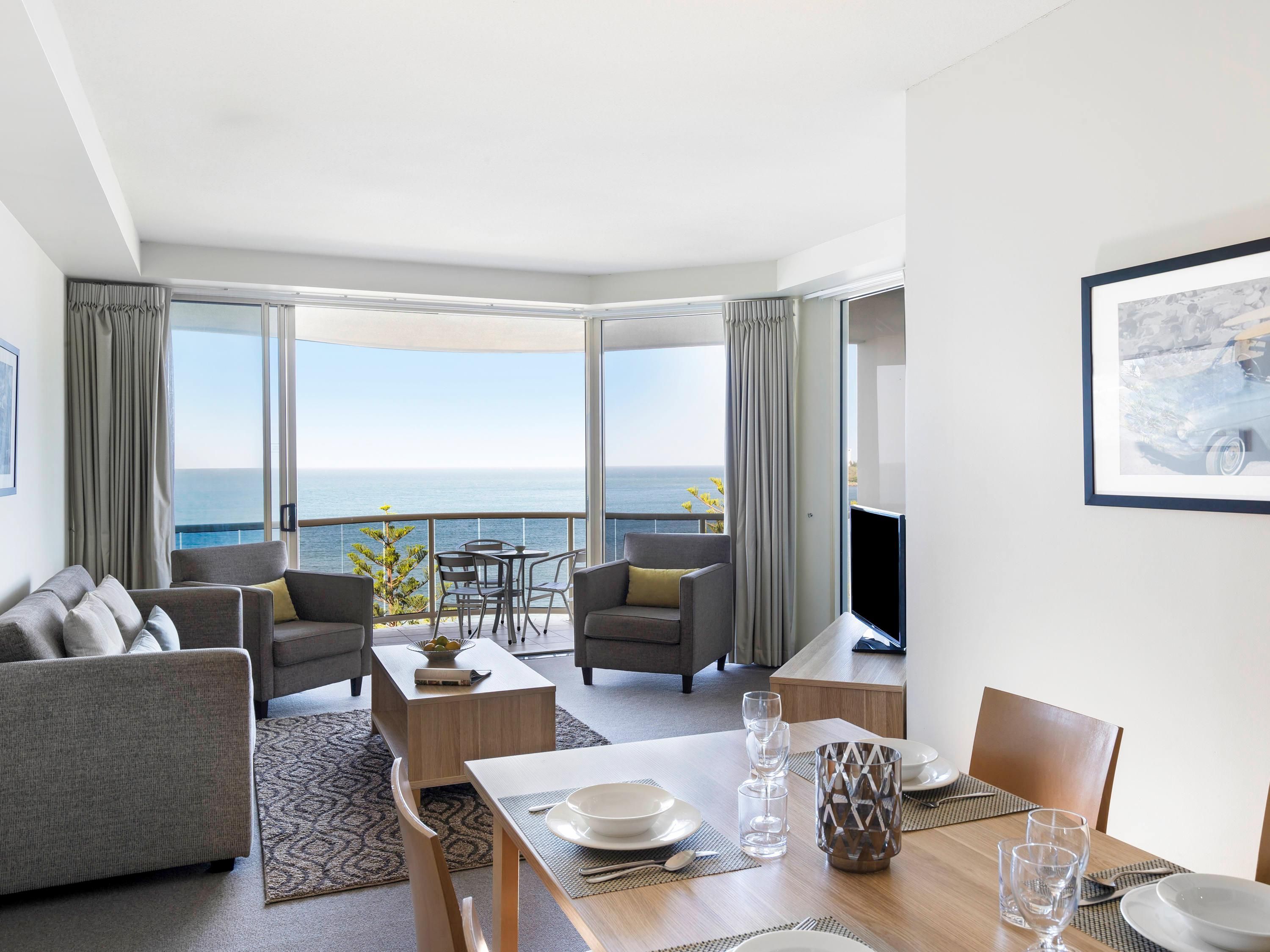 Una sala moderna con comedor, ventanas amplias y vista al mar.