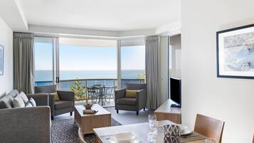 Una sala moderna con comedor, ventanas amplias y vista al mar.
