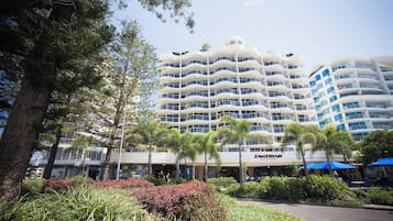 Ein mehrstöckiges Hotel mit Balkonen, einem Restaurant und üppiger Vegetation.
