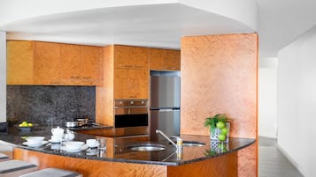 A modern kitchen with wooden cabinetry, a granite countertop, stainless steel appliances, and a central island with bar stools.