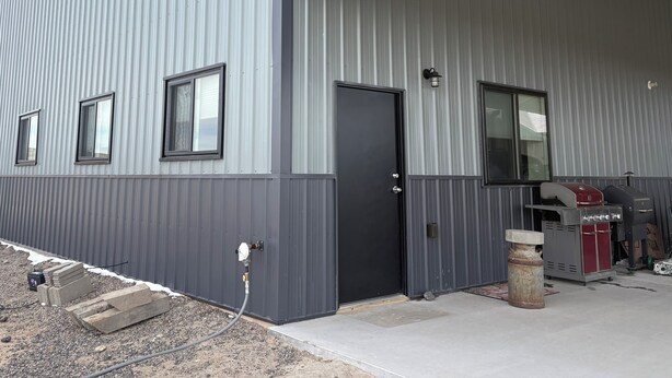 En stor industribygning med metalfacade, en sort dør og et overdækket område til varelevering.