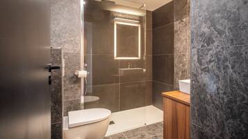 A modern bathroom with a toilet, sink, and shower area.