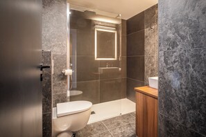 Ein modernes Badezimmer mit Toilette, Waschbecken und Duschbereich.