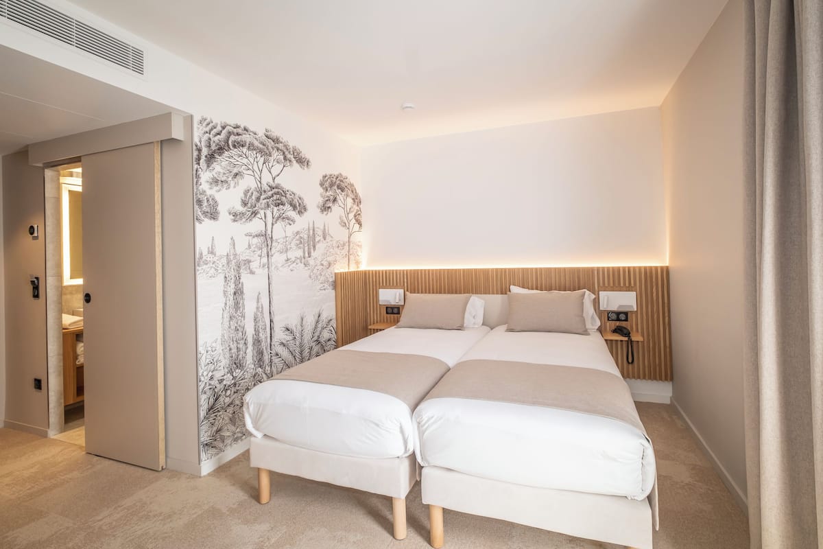 A double bed with a headboard, bedside tables, and a wall mural.