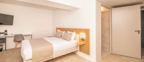A modern bedroom with a bed, bedside table, and a desk with a chair.
