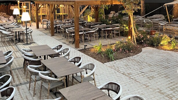 An outdoor seating area with tables and chairs, surrounded by plants and trees. - Hotel le Relais des Brasseurs (Aubagne)