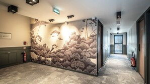 A hallway with a mural of trees and a fire extinguisher on the left. - Hotel le Relais des Brasseurs (Aubagne)