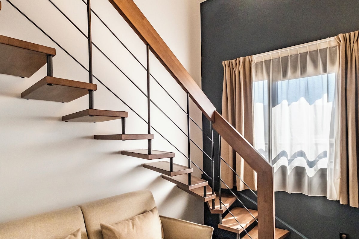 A modern interior with a staircase, a sofa, and pendant lighting.