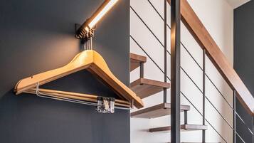 Un interior modern amb una escala de fusta, una làmpada penjant i un sofà beix.
