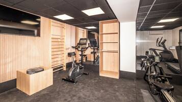 Una palestra con attrezzature per esercizi, armadietti in legno e uno specchio a parete.