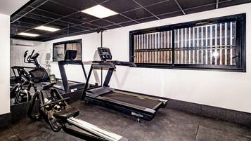 Une salle de sport équipée de tapis de course, de vélos d’appartement et d’un appareil d’aviron.