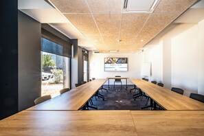 A conference room with a long wooden table, black chairs, and a projector screen displaying a welcome message. - Hotel le Relais des Brasseurs (Aubagne)