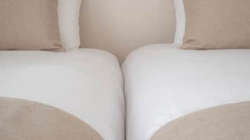 Una cama doble con dos almohadas, cabecera de madera y pared lisa.