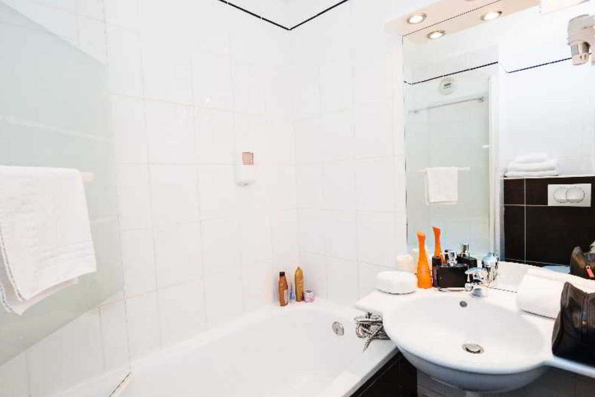 Un baño moderno con bañera, lavamanos y espejo.